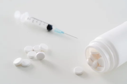 NAD injections vs pills comparison showing a syringe and capsules side by side